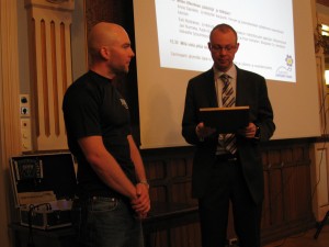 Timo Koivisto luovuttamassa tunnustuspalkintoa Teemu Tenhuselle.